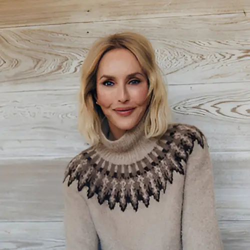 Sarah Woodhead Bacon profile pciture Sarah Woodhead Bacon Official Portrait of Sarah Woodhead Bacon seated casually on an outdoor sofa against a textured wooden wall, wearing a patterned knit sweater and jeans. A global conservation advisor and advocate for biodiversity, she smiles warmly at the camera.